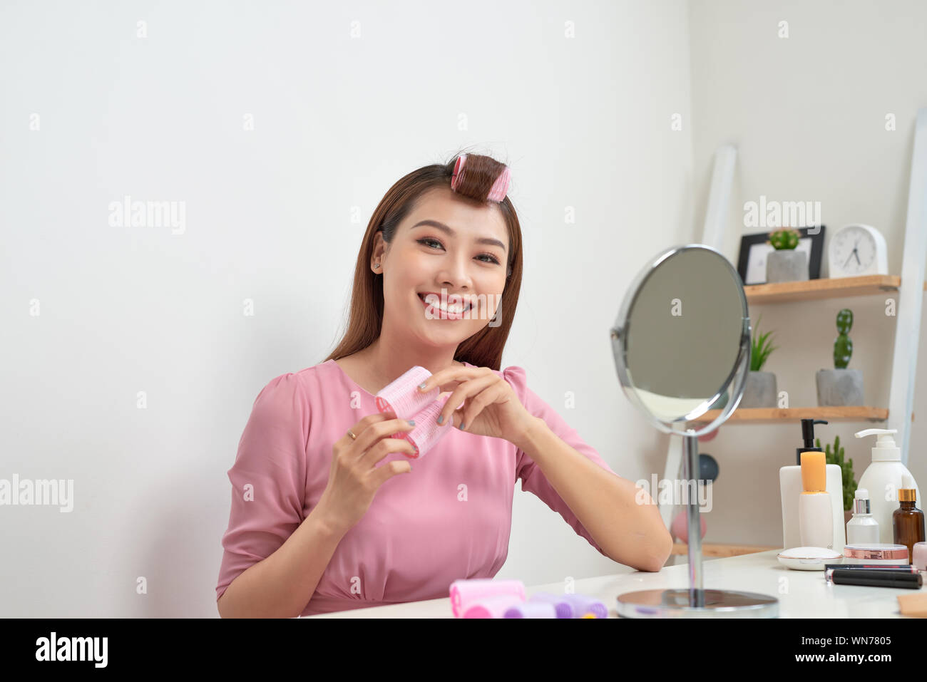 Kopf und Schultern Portrait von schöne asiatische Frau Haar Lockenwickler in Spiegel mit breitem Lächeln suchen, Home Interior auf Hintergrund Stockfoto
