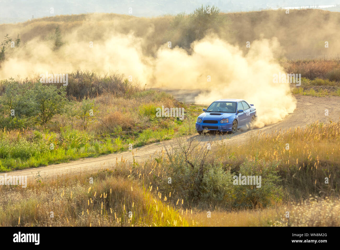 Sommer sonnigen Tag. Dirt Track für die Rallye. Ein Auto fährt durch eine Kurve und macht eine Menge Staub. Slow Motion 02. Stockfoto