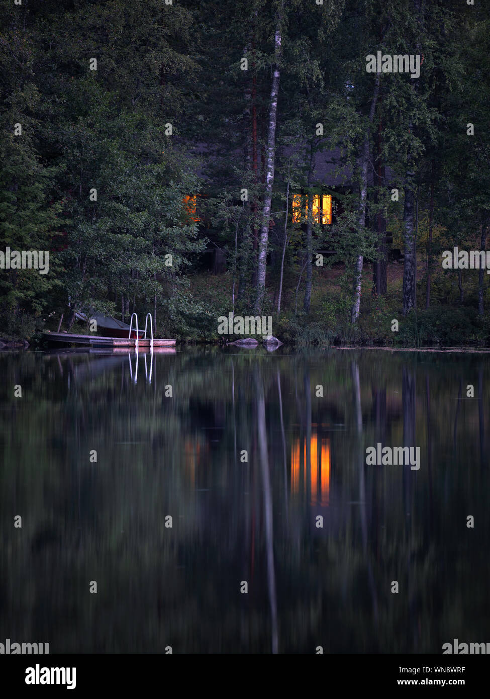 Idyllisches Ferienhaus mit gemütlicher Cottage und Fenster Licht in ruhiger Sommer Nacht in Finnland Stockfoto