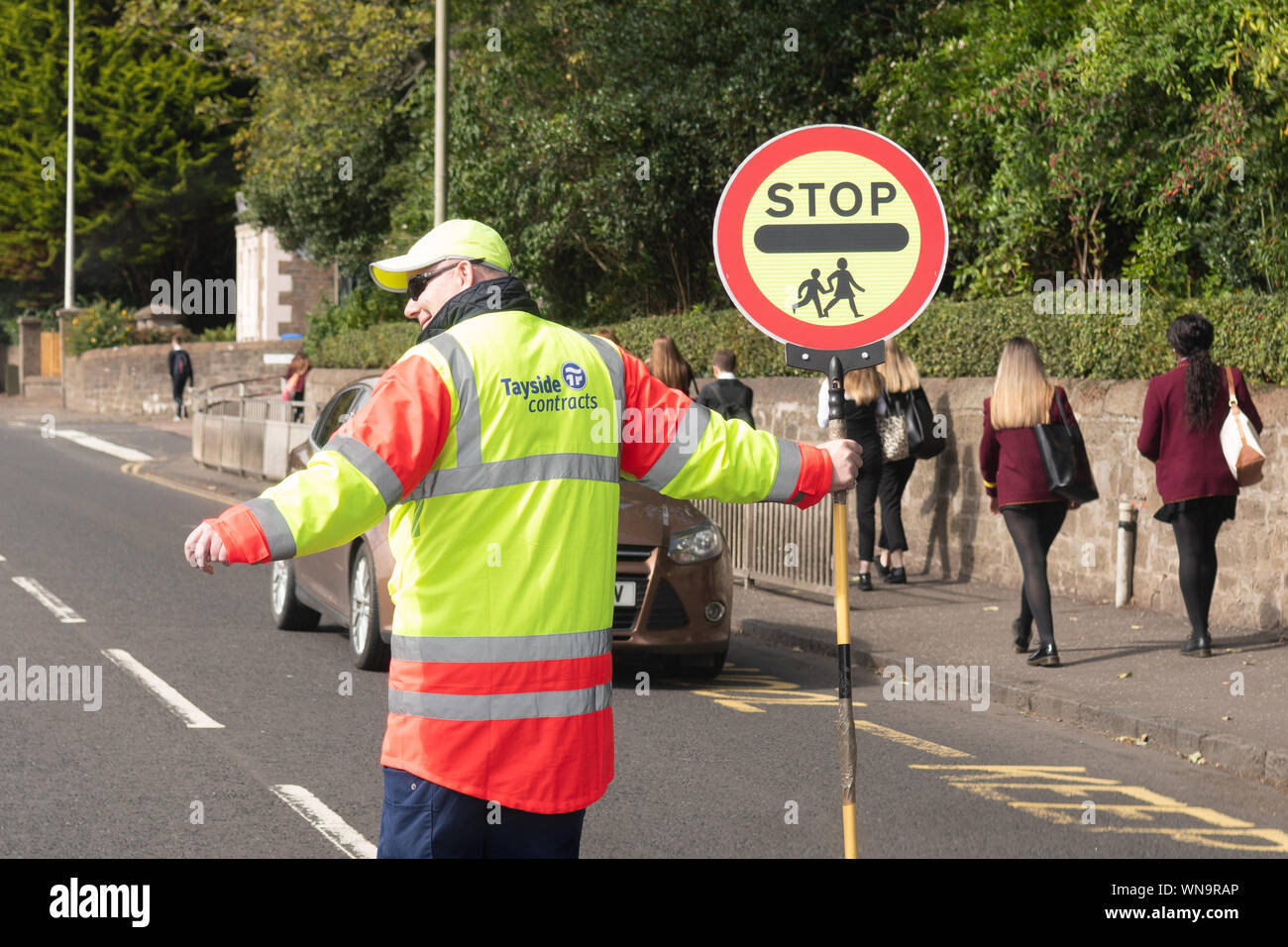Lollipop Mann Person und Zeichen außerhalb der Schule in Schottland, Großbritannien Stockfoto