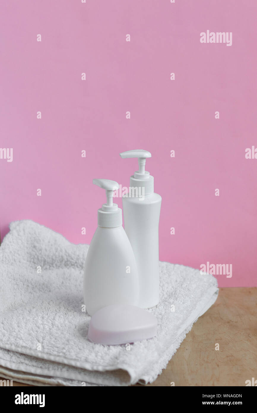 Leere Plastikflaschen und Seife auf Dusche Handtuch in Pastelltönen gehaltene moderne Einrichtung. Hygiene Kosmetik Konzept. Kopieren Sie Platz. Stockfoto