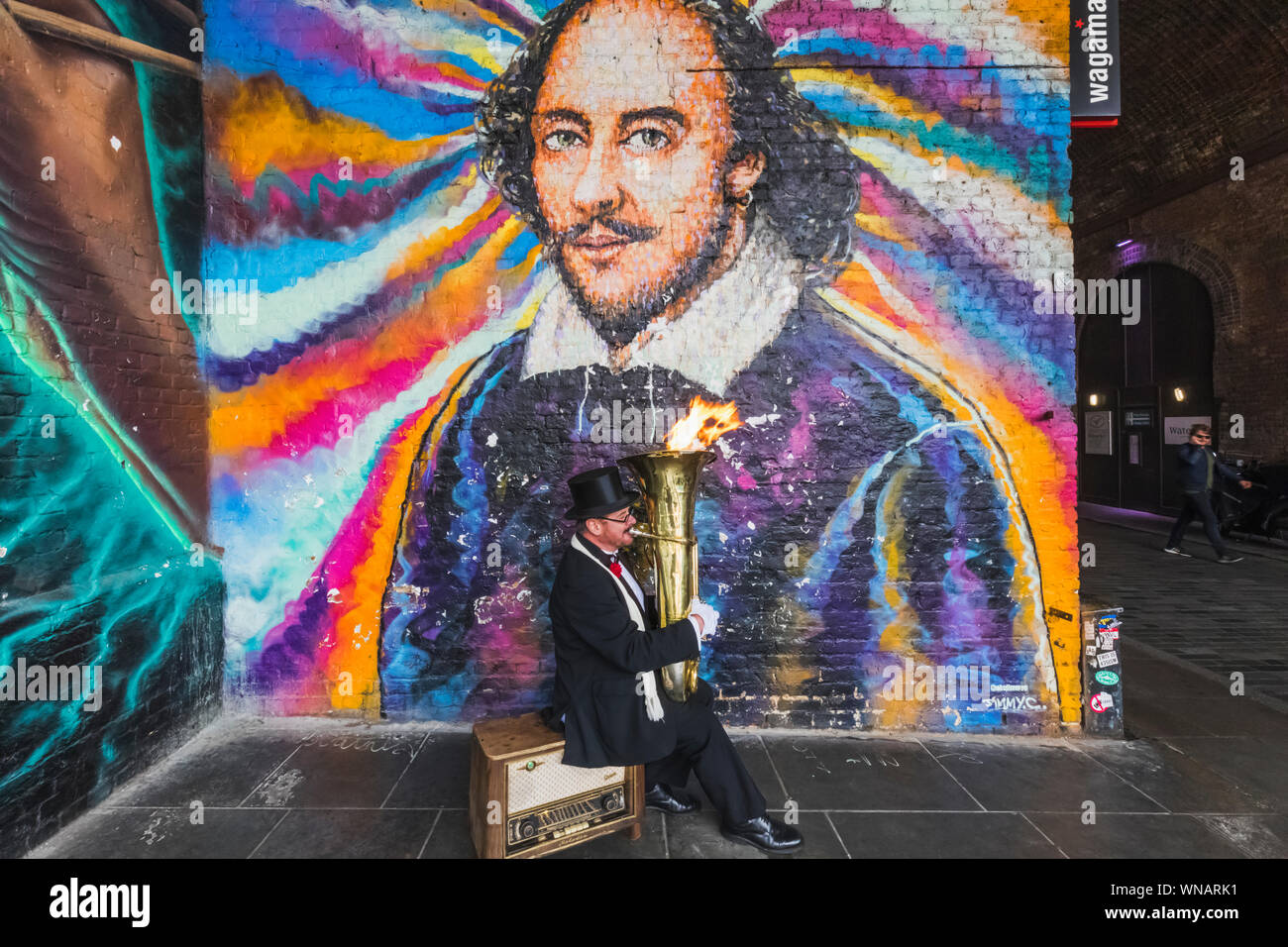 England, London, Southwark, Bankside, Straßenmusiker spielen Feuer Tuba bläst Vor William Shakespeare Wandbild Stockfoto