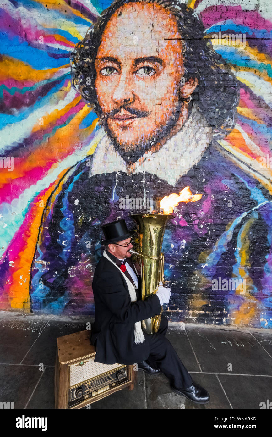 England, London, Southwark, Bankside, Straßenmusiker spielen Feuer Tuba bläst Vor William Shakespeare Wandbild Stockfoto