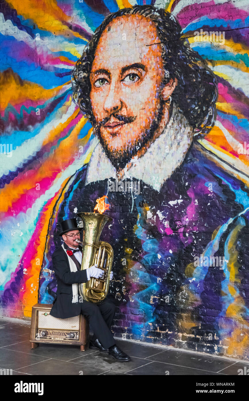 England, London, Southwark, Bankside, Straßenmusiker spielen Feuer Tuba bläst Vor William Shakespeare Wandbild Stockfoto