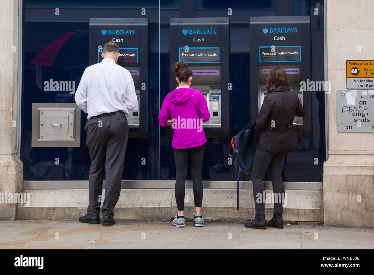 Käufer nutzen drei Barclays Bank-Geldautomaten oder Geldautomaten außerhalb einer Filiale der Barclays Bank in der Hauptstraße. Stockfoto