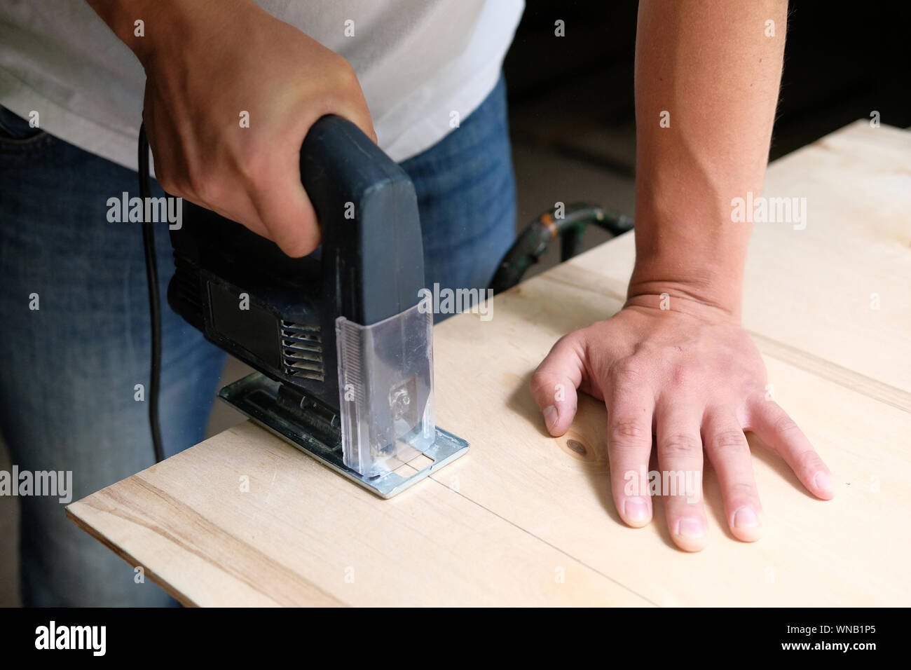 Tischler ist Sägen ein Sperrholz mit elektrischen Stichsäge Maschine in der  Schreinerei. Nahaufnahme der Hand mit Jigsaw. Zimmerei Konzept  Stockfotografie - Alamy
