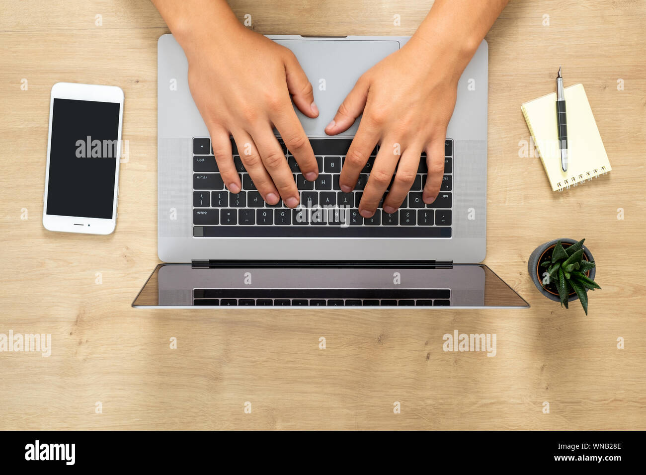 Ansicht von oben menschliche Hände arbeiten an modernen Laptop, online surfen, indem Sie einen Text, Surfen im Internet. Flach Holz Büro Schreibtisch Tisch mit Laptop, s Stockfoto