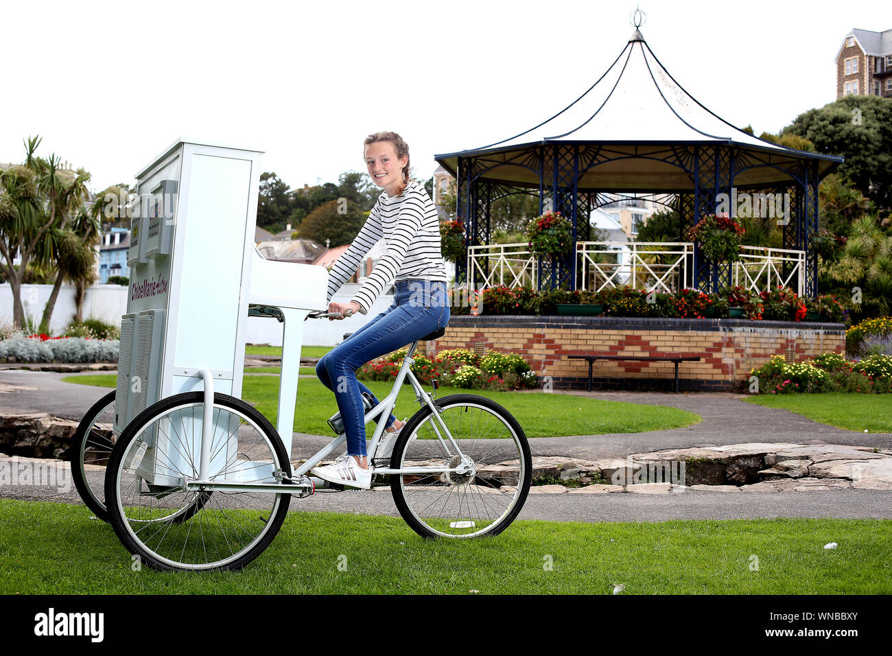 Ilfracombe busker Chloe Aston abgebildet auf ihre einzigartige piano Bike, die sie verwendet, um die Massen zu unterhalten, wenn Sie führt Stockfoto