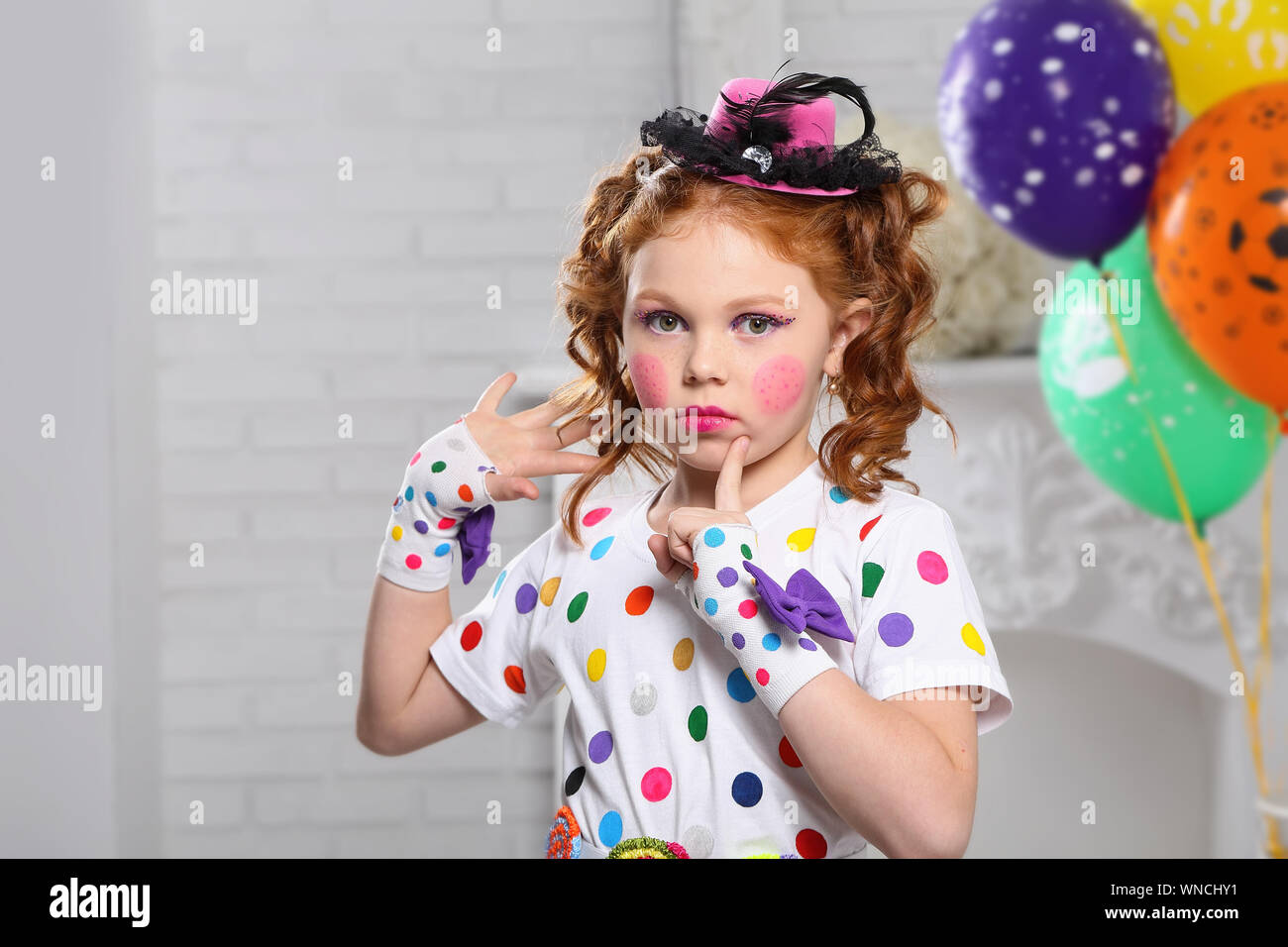 Rothaarige Mädchen im Bild Clown. In einem weißen Zimmer mit Luftballons. Stockfoto