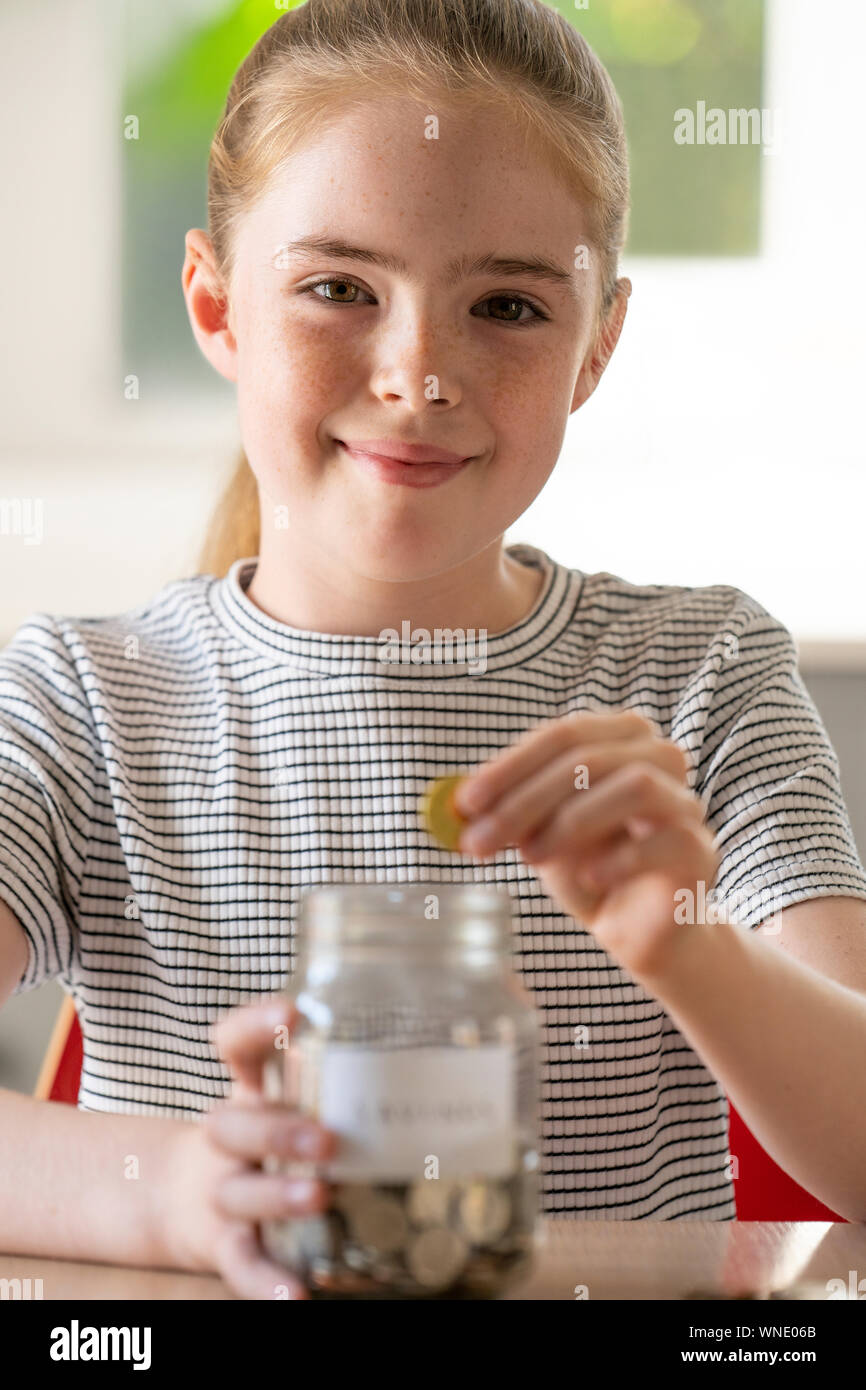 Portrait von Mädchen, Münzen in Glas Glas mit der Aufschrift Einsparungen zu Hause Stockfoto