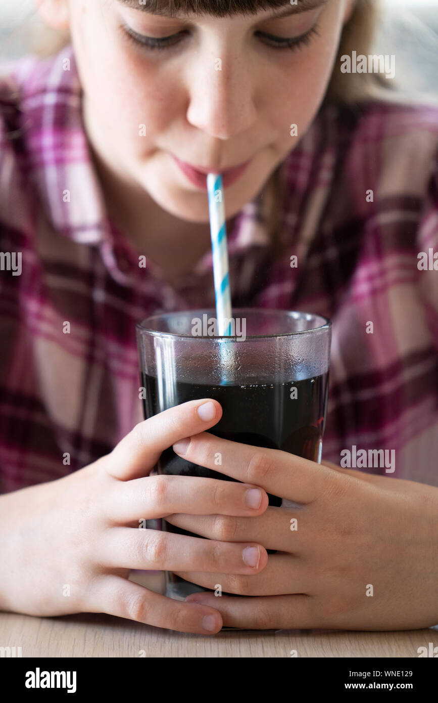 Mädchen Trinken von zuckerhaltigen Fizzy Soda aus Glas mit Strohhalm Stockfoto