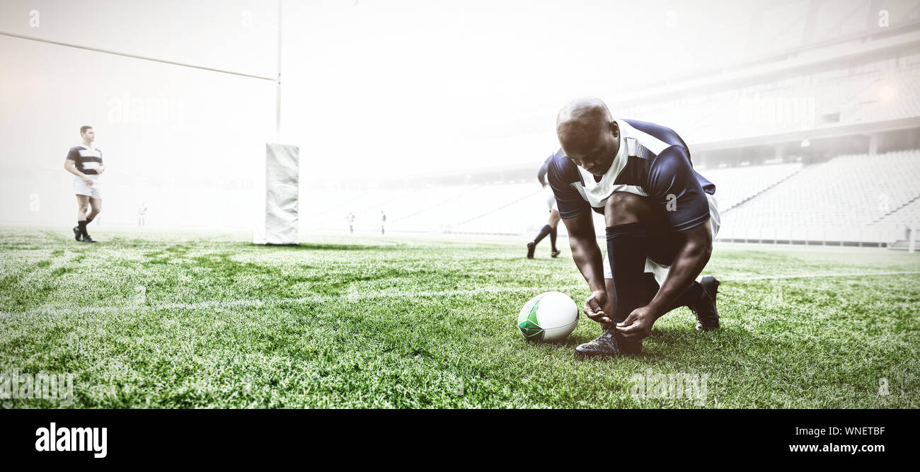 African American male Rugby player Schnürsenkel binden im Stadion Stockfoto
