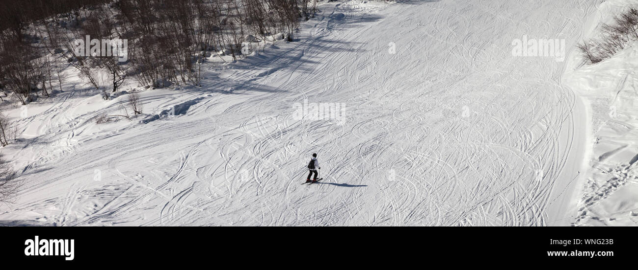 Skifahrer bergab auf verschneiten Skipiste bei Sun winter Tag. Panoramablick. Stockfoto