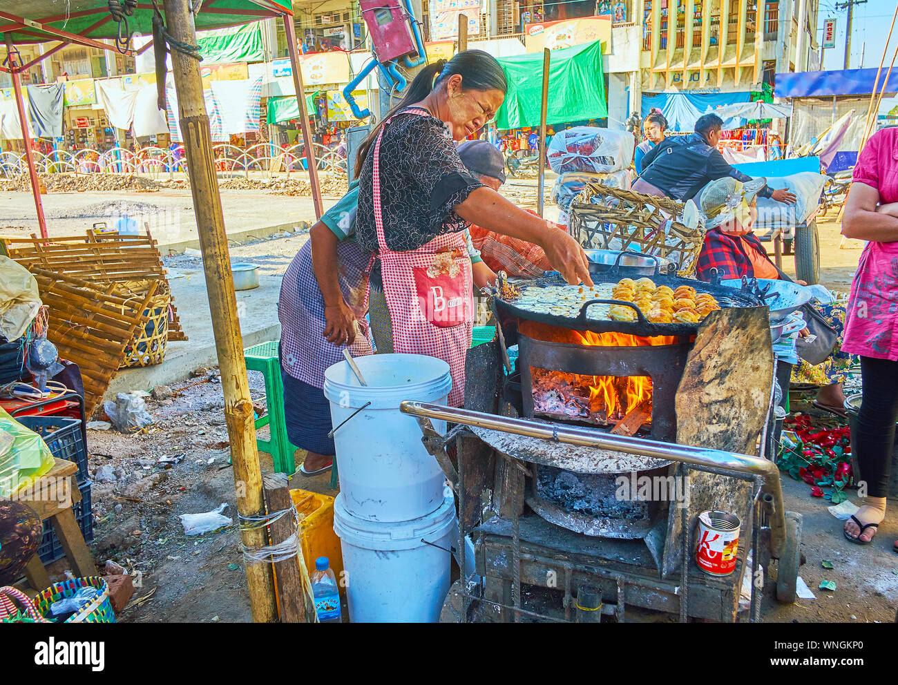 TAUNGGYI, MYANMAR - 20. FEBRUAR 2018: Die Straße Kochen macht mote-lin-ma-Yar (Snack's Paar) kleine Pfannkuchen in großen Pan, stehend auf dem Steinofen Stockfoto