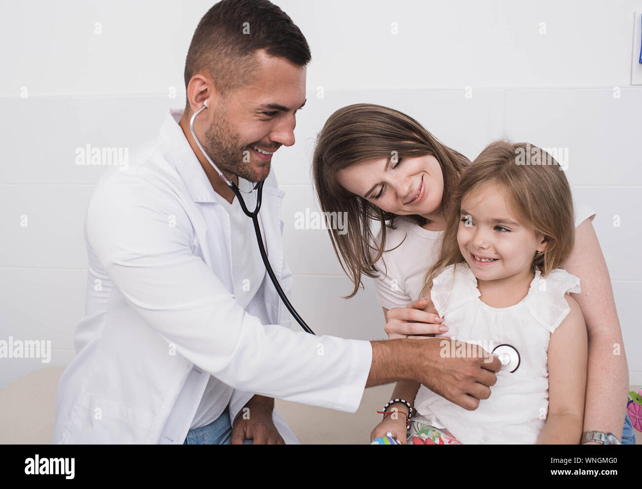 Positiven pädiatrischen Arzt während der Arbeit mit einem Kind, die Mutter mit einem Kind von einem Kinderarzt untersucht Stockfoto