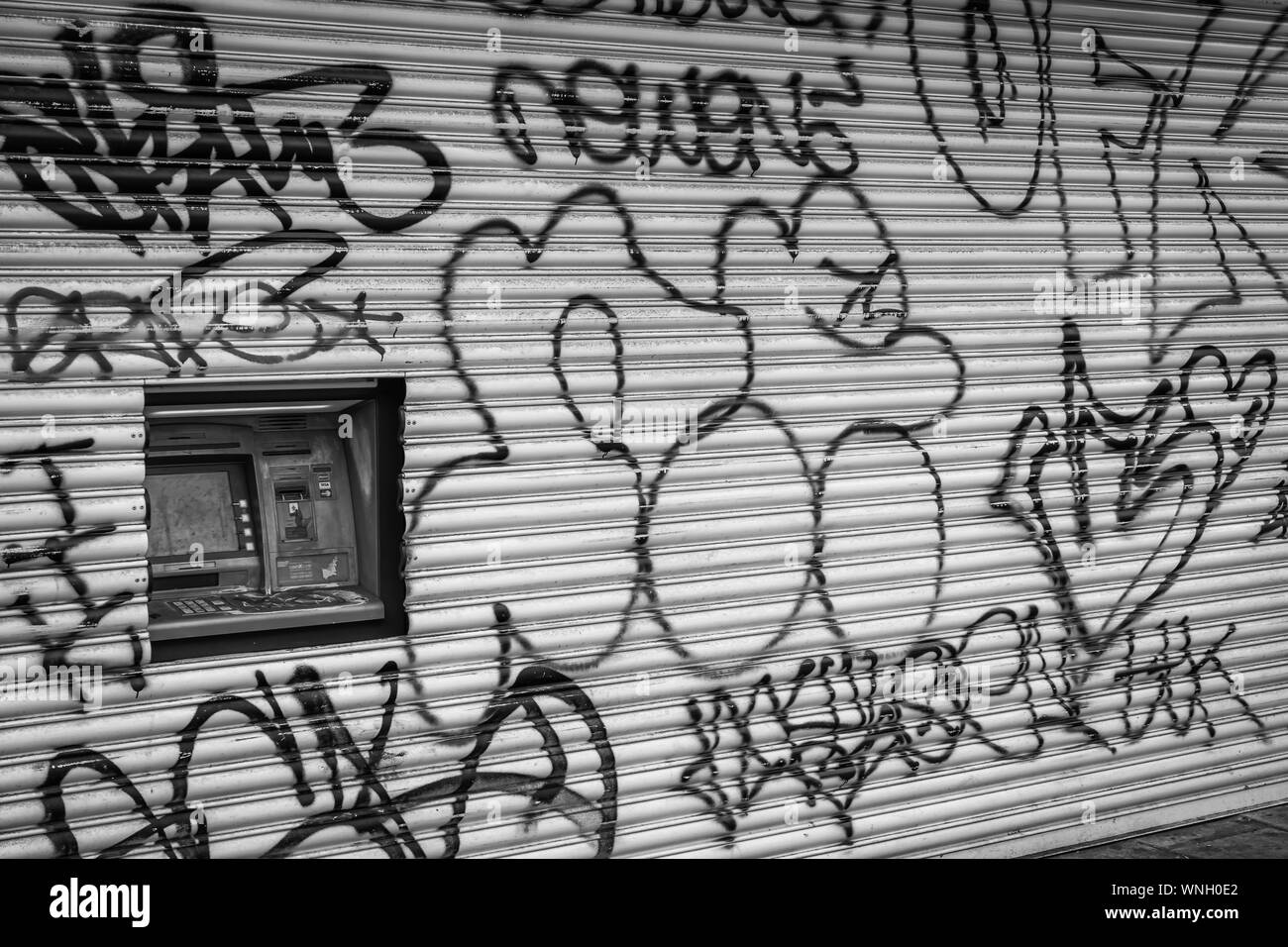 London Road, Brighton UK 09/06/2019 Graffiti auf's shop Fensterläden mit Loch für beschädigte cashpoint Stockfoto