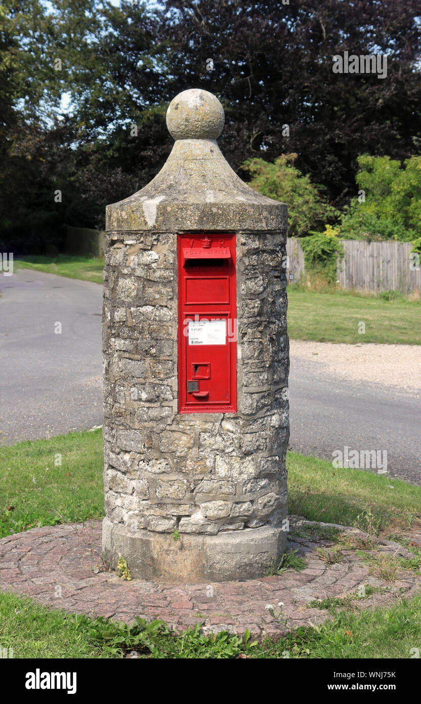 Englisches Dorf Red Post Box Set in einem runden Stein Struktur Stockfoto