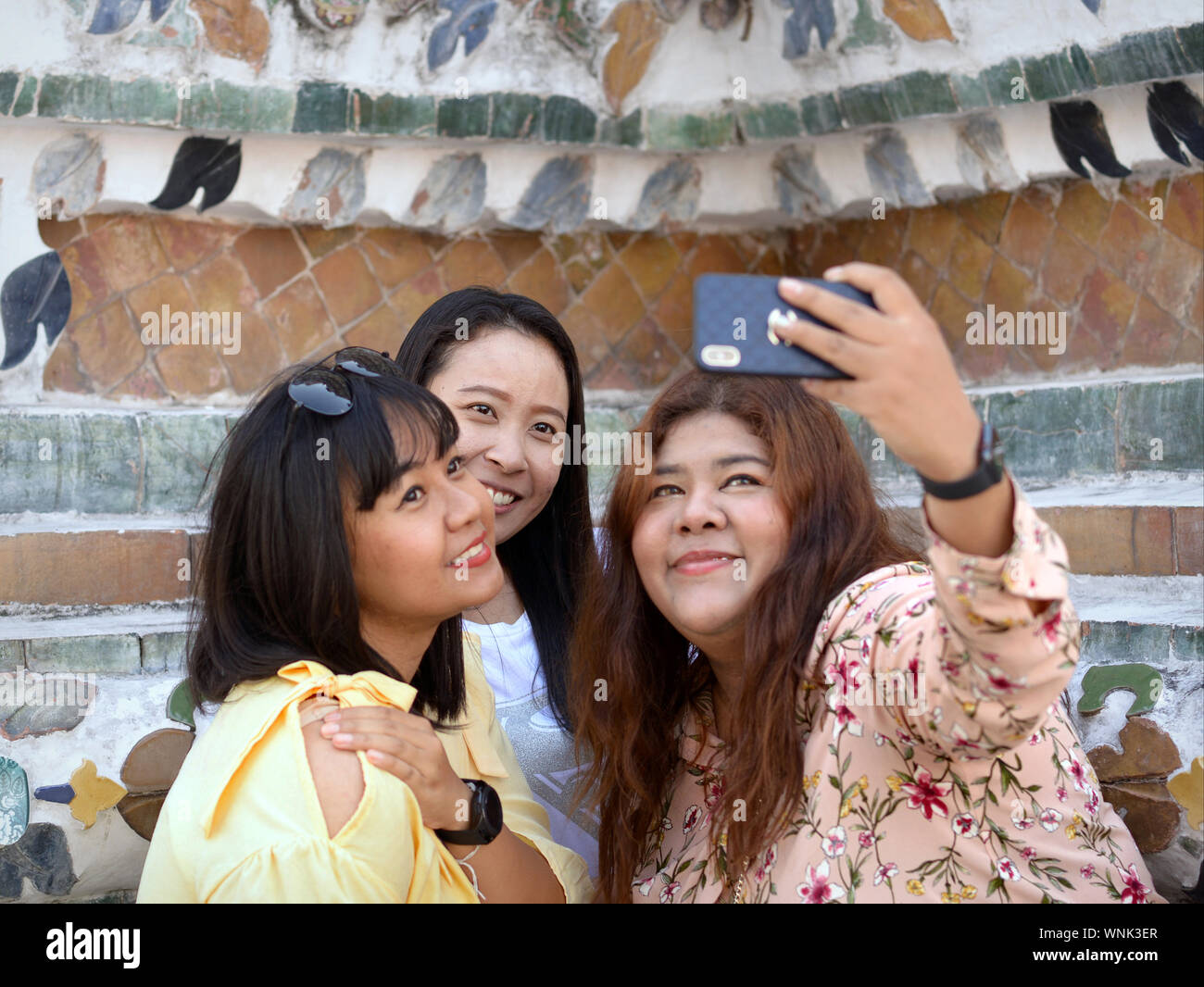 Drei junge thailändische Frauen nehmen einen wefie mit Ihrem Handy auf der Bangkok Wat Arun Tempel. Stockfoto