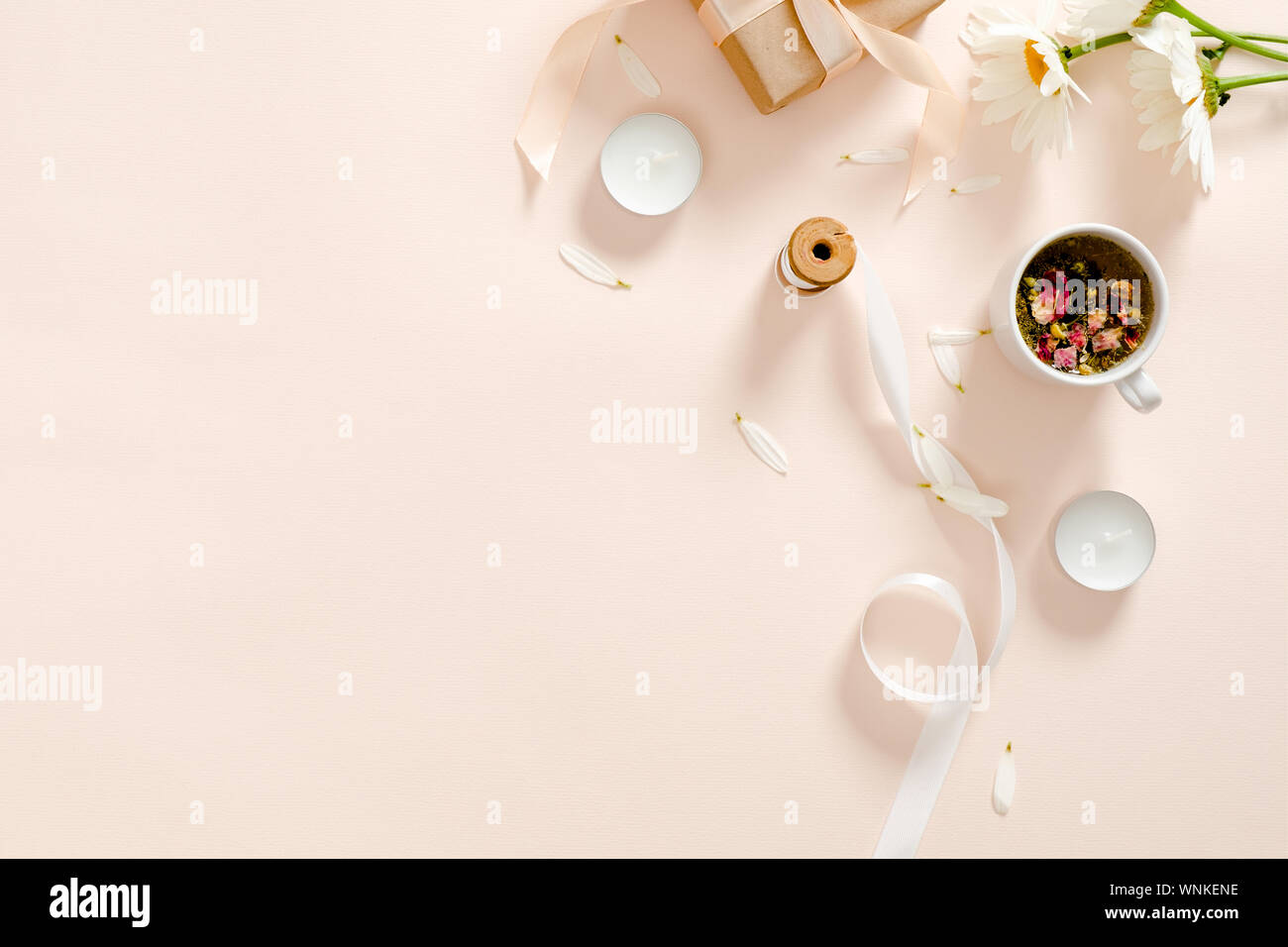 Kräutertee, Kerzen, Band, Geschenkbox, Kamille Blüte Pastell rosa Hintergrund. Minimale flach Stil Zusammensetzung, Ansicht von oben, Overhead. Stockfoto