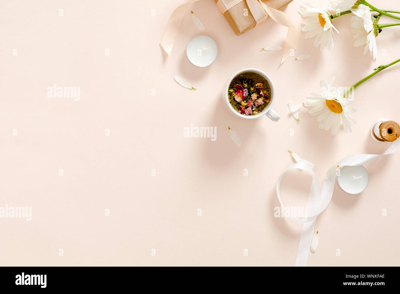 Kräutertee, Kerzen, Band, Geschenkbox, Kamille Blüte Pastell rosa Hintergrund. Minimale flach Stil Zusammensetzung, Ansicht von oben, Overhead. Stockfoto