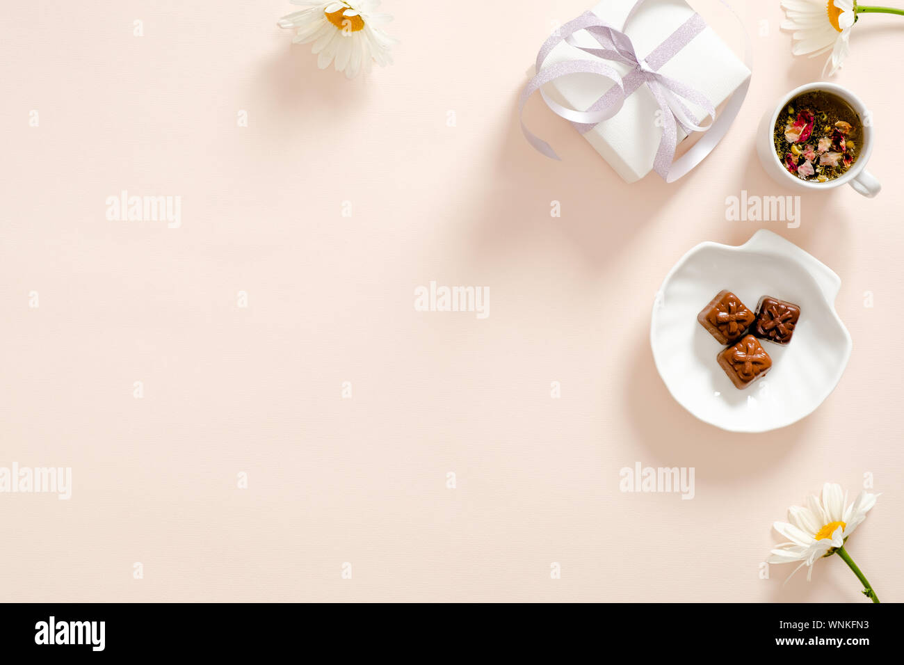 Romantische flatlay Komposition mit Geschenkbox, Kräutertee, Band, Daisy Kamille Blüte Pastell rosa Hintergrund. Feminine home office Schreibtisch Konzept. F Stockfoto