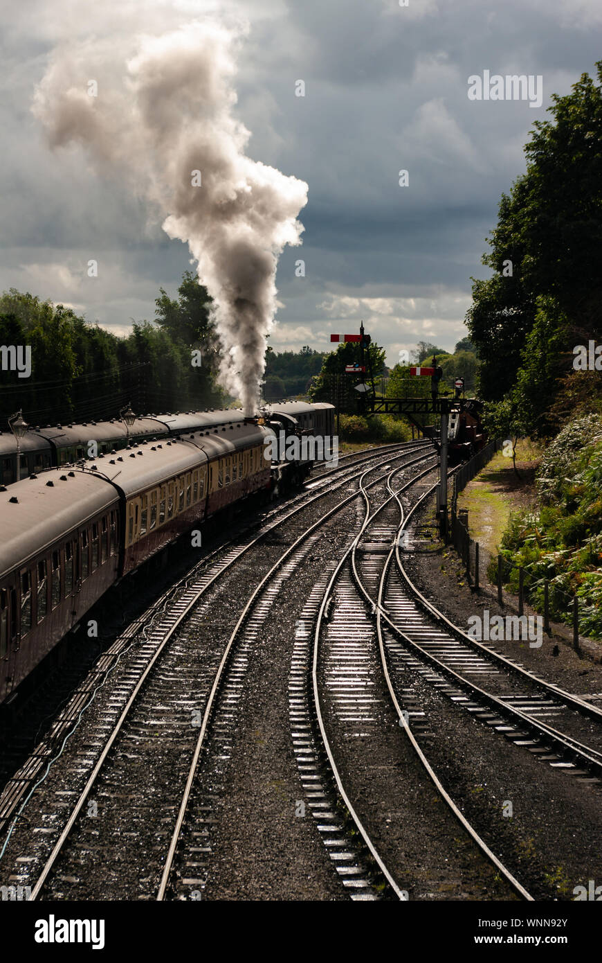 Der Dampfzug verlässt den Bahnhof Bridgnorth auf der Severn Valley Railway, Shropshire, mit einer Rauchwolke, die von der Sonne beleuchtet wird Stockfoto