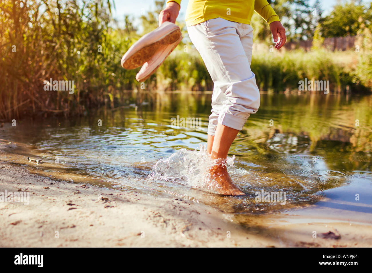 Frau mittleren Alters barfuß wandern am Ufer auf Herbst Tag. Ältere Dame Spaß im Wald die Natur genießen. Nahaufnahme der Beine Stockfoto