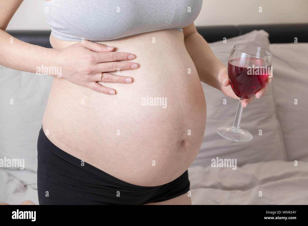 Schwangere Frau, Alkohol zu trinken, Mädchen in der Schwangerschaft halten Glas Wein Stockfoto