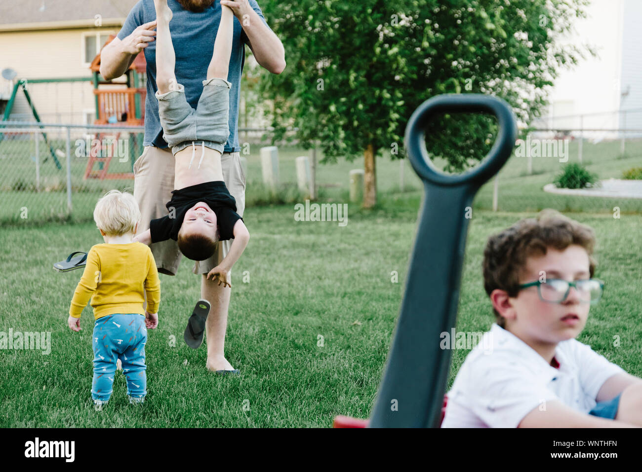 Vater und Jungen spielen in einem vorstädtischen Hinterhof im Sommer. Stockfoto