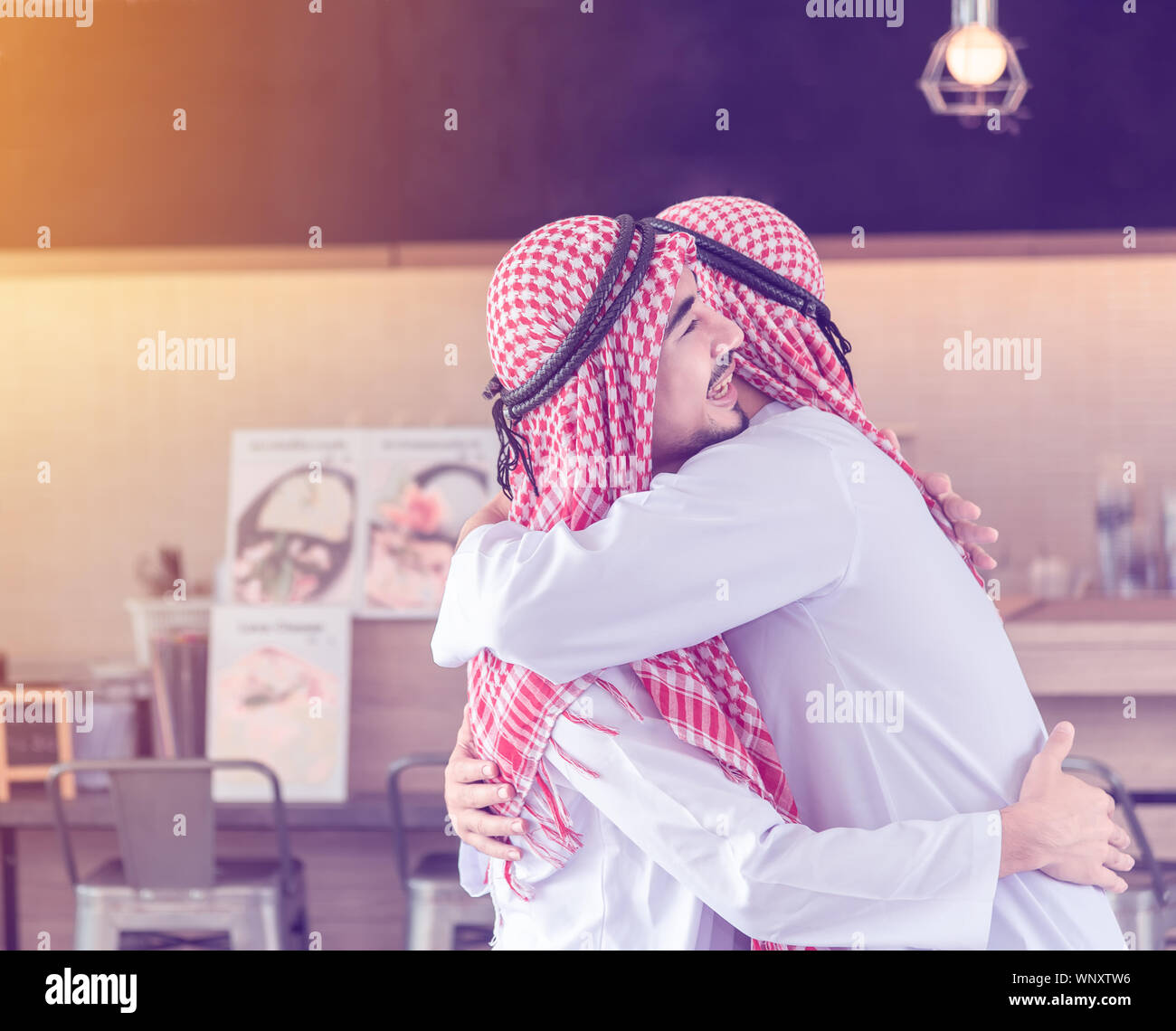 Zwei arabische Männer, die Freunde zusammen sind, umarmen und Lächeln, wenn Sie versehentlich an den Cafe & Restaurant am Morgen treffen Stockfoto