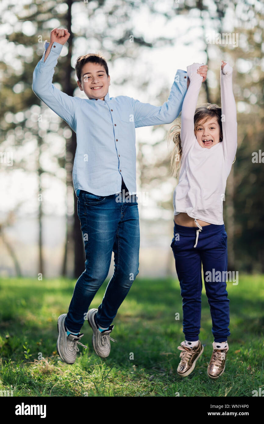 Junge und Mädchen springen und in die Natur genießen. Glückliche Kinder spielen im Park. Stockfoto