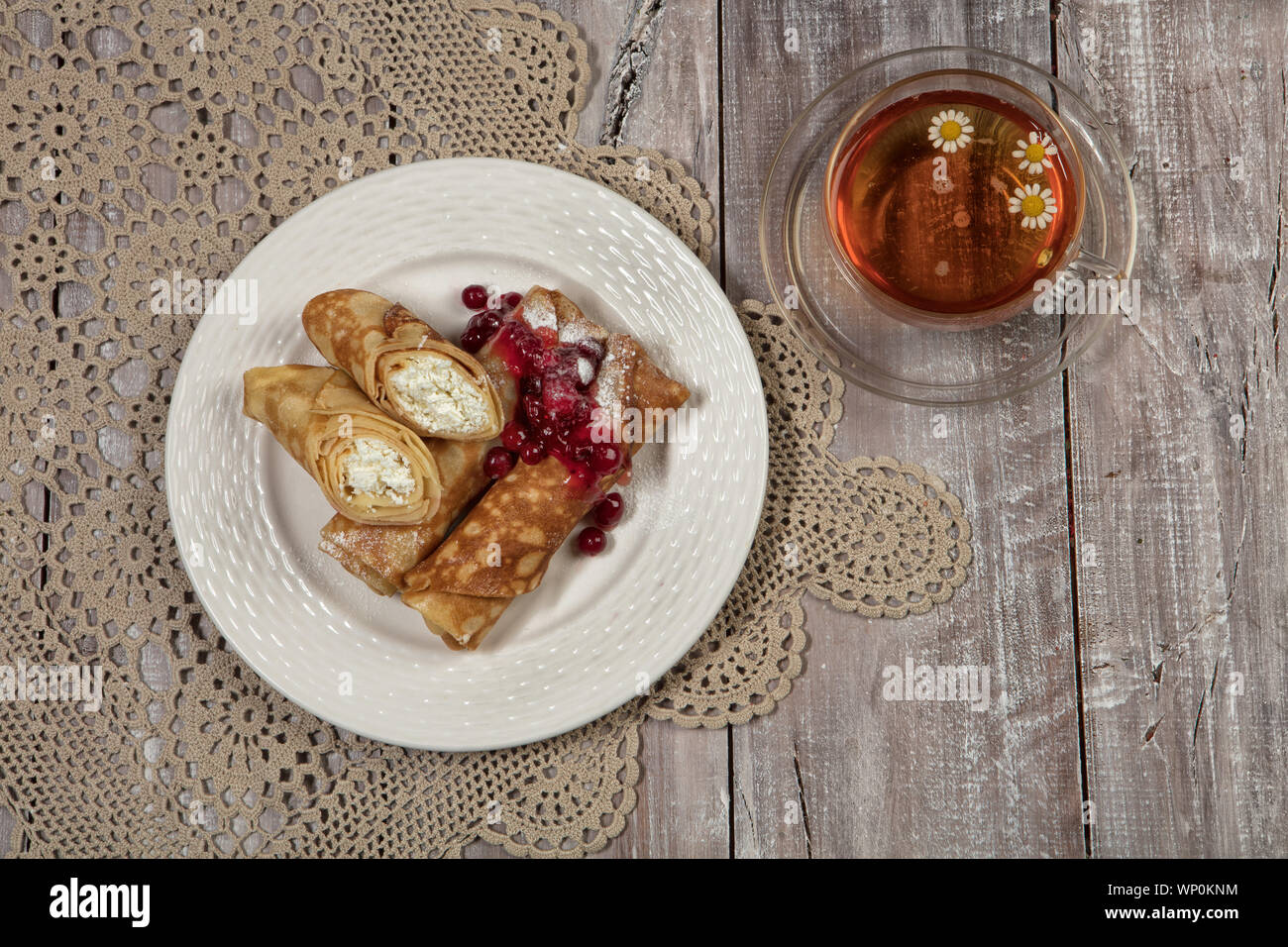 Mit Pfannkuchen mit Fleisch und Tasse Tee auf einem alten hölzernen Hintergrund Platte Stockfoto