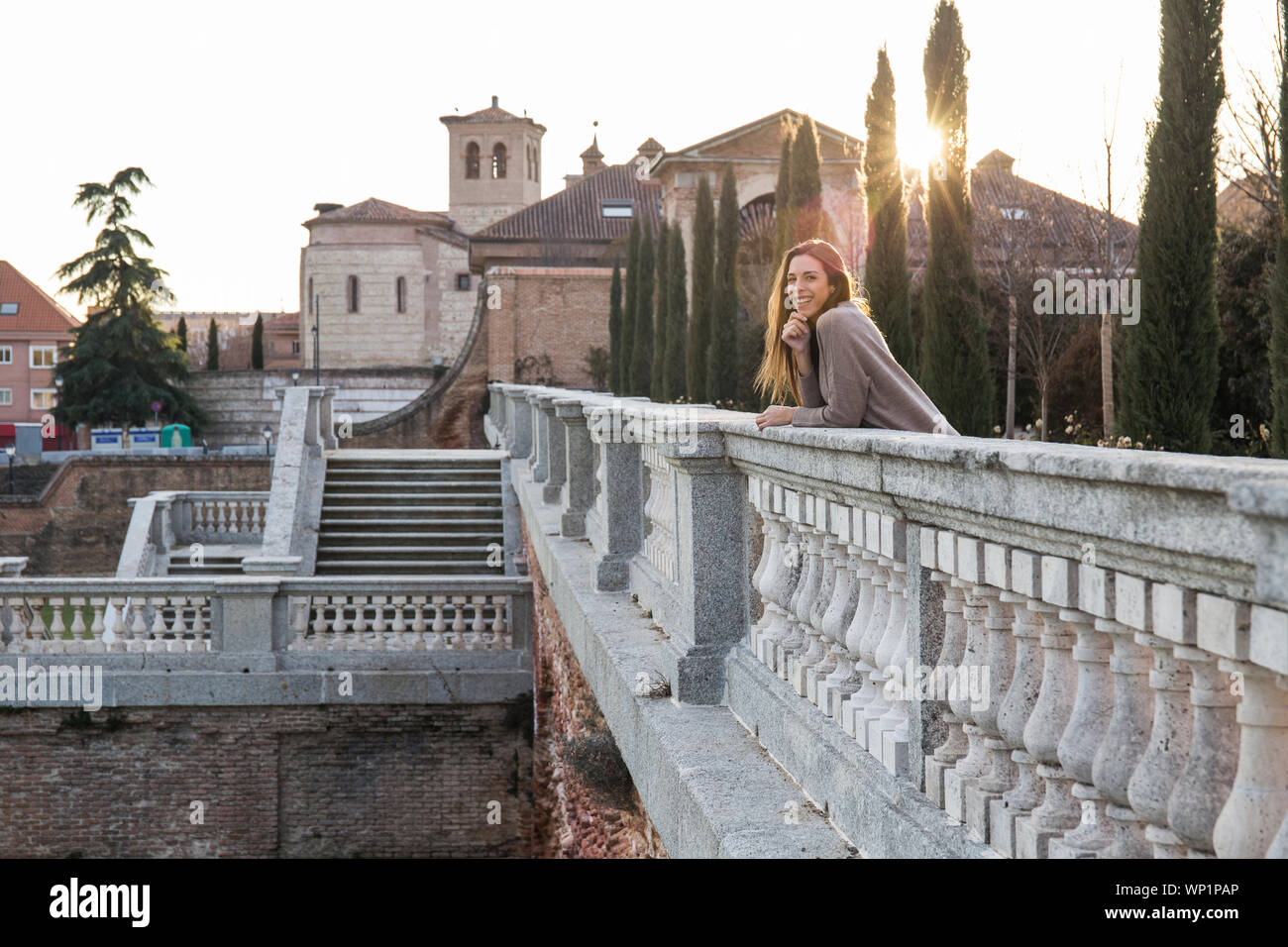 Lächelnde junge Frau lehnte sich auf eine Brücke aus Stein Stockfoto