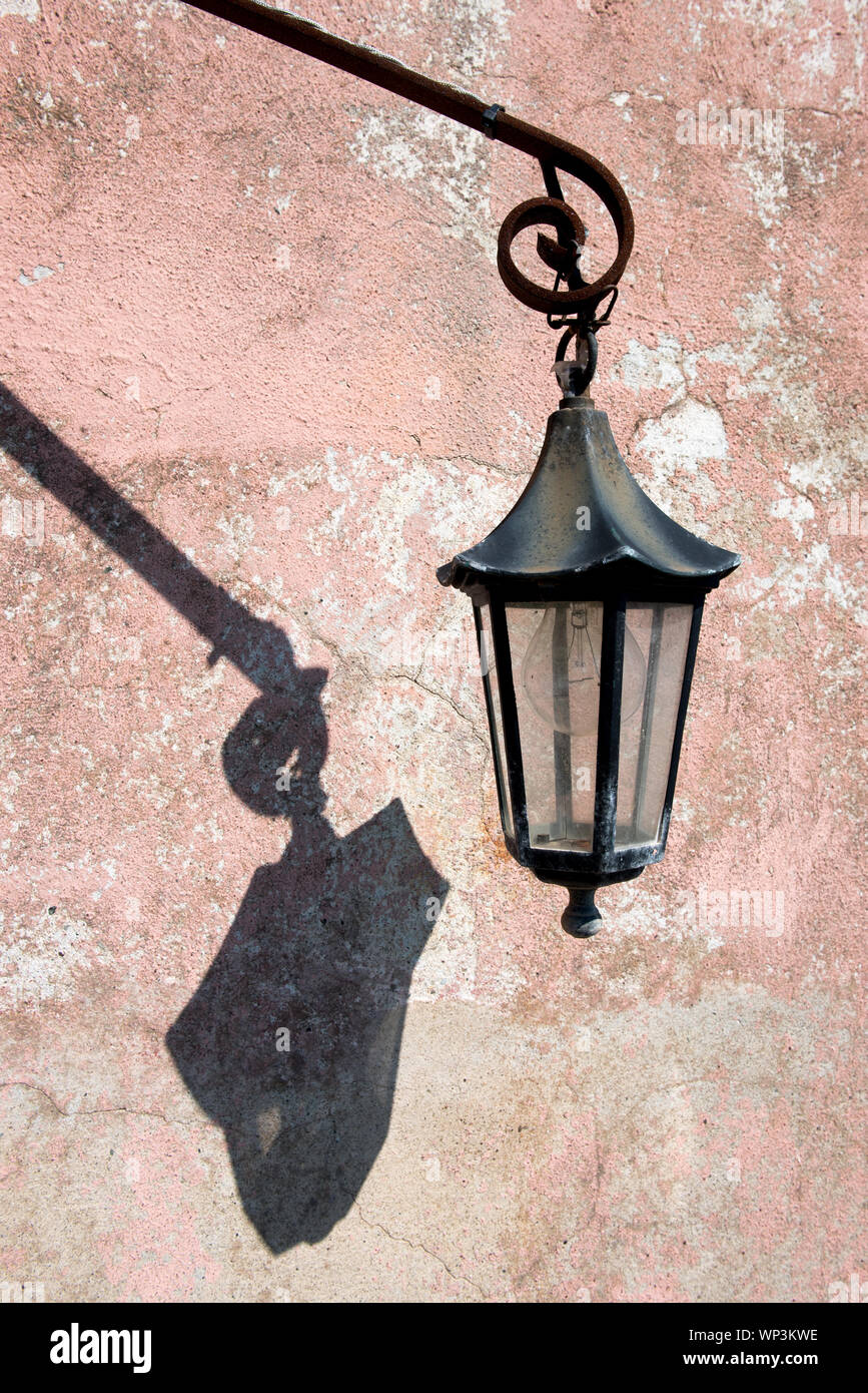 Alte vintage Metall außen Laterne mit Schatten in der Sonne an einem Grunge alte Mauer mit Peeling rosa Farbe in der Nähe zu sehen. Stockfoto