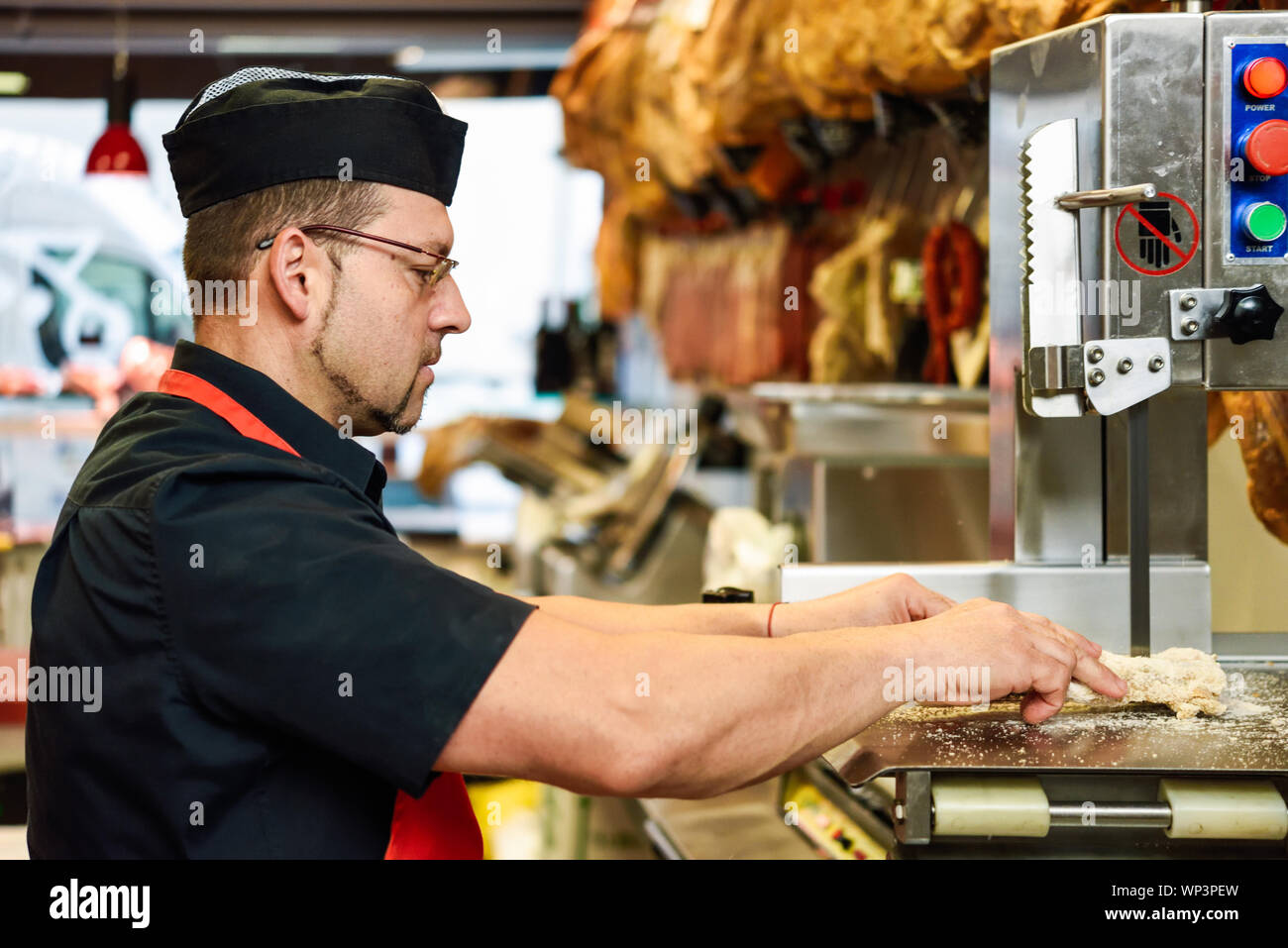 Männliche Metzger schneiden Schinken Knochen in einer Maschine Stockfotografie
