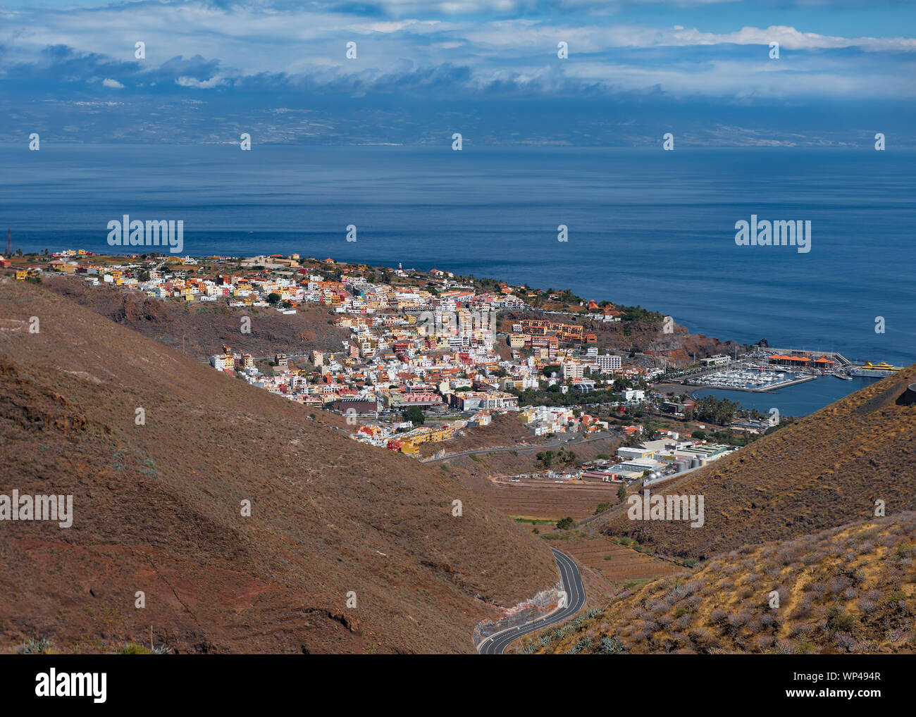 Blick auf die Insel Teneriffa unter den Wolken. Mit San Sebastian de la Gomera, das Kapital in den Vordergrund mit dem Atlantischen Ozean dazwischen. Klar Stockfoto