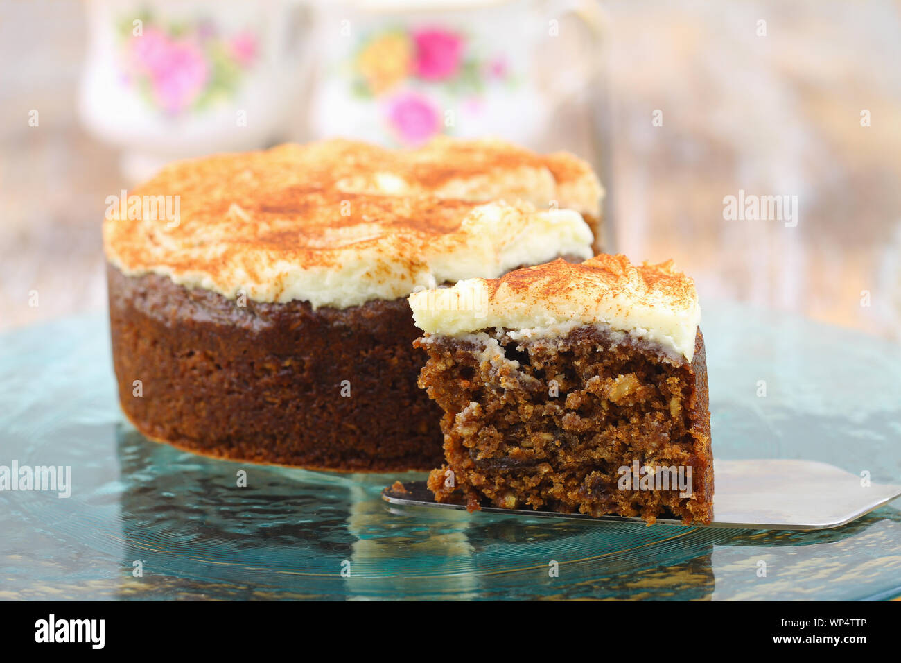 Scheibe der köstliche Walnuß und Karottenkuchen mit marzepain Zuckerglasur mit ganzen Kuchen im Hintergrund Stockfoto