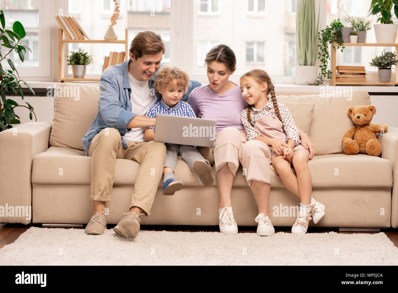 Junge Familie mit Laptop surfen im Netz bei der Wahl Film oder Cartoons Stockfoto