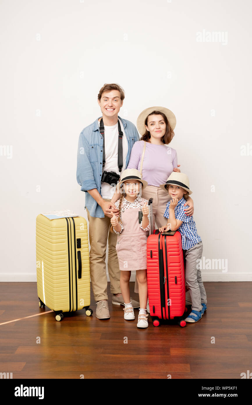 Glückliche junge casual Vater, Mutter, Sohn und Tochter mit Gepäck im Studio Stockfoto