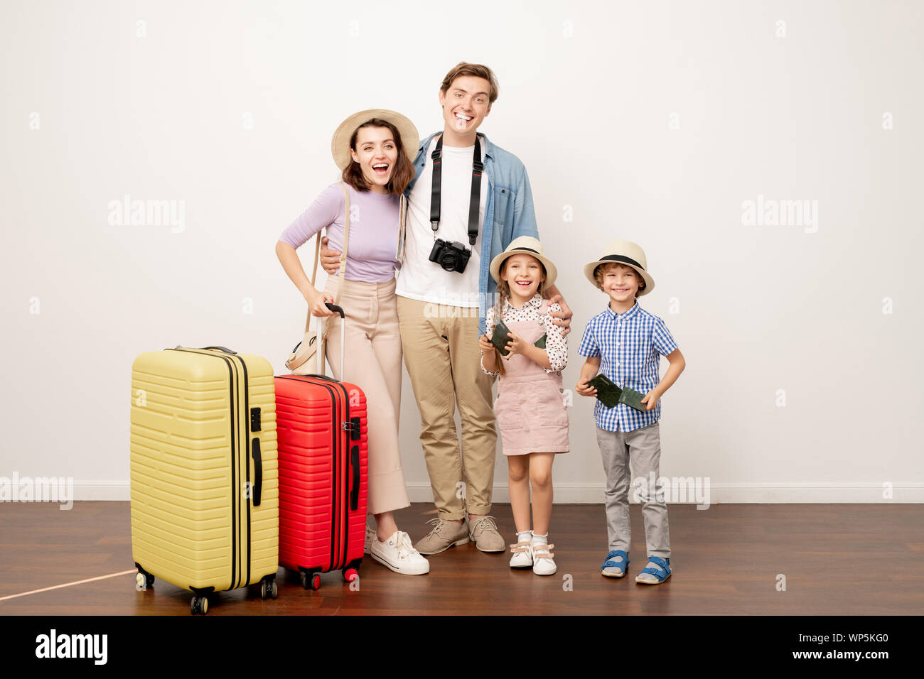 Aufgeregt Familie von zwei Eltern und ihren süßen Zicklein in der casualwear mit Koffer Stockfoto