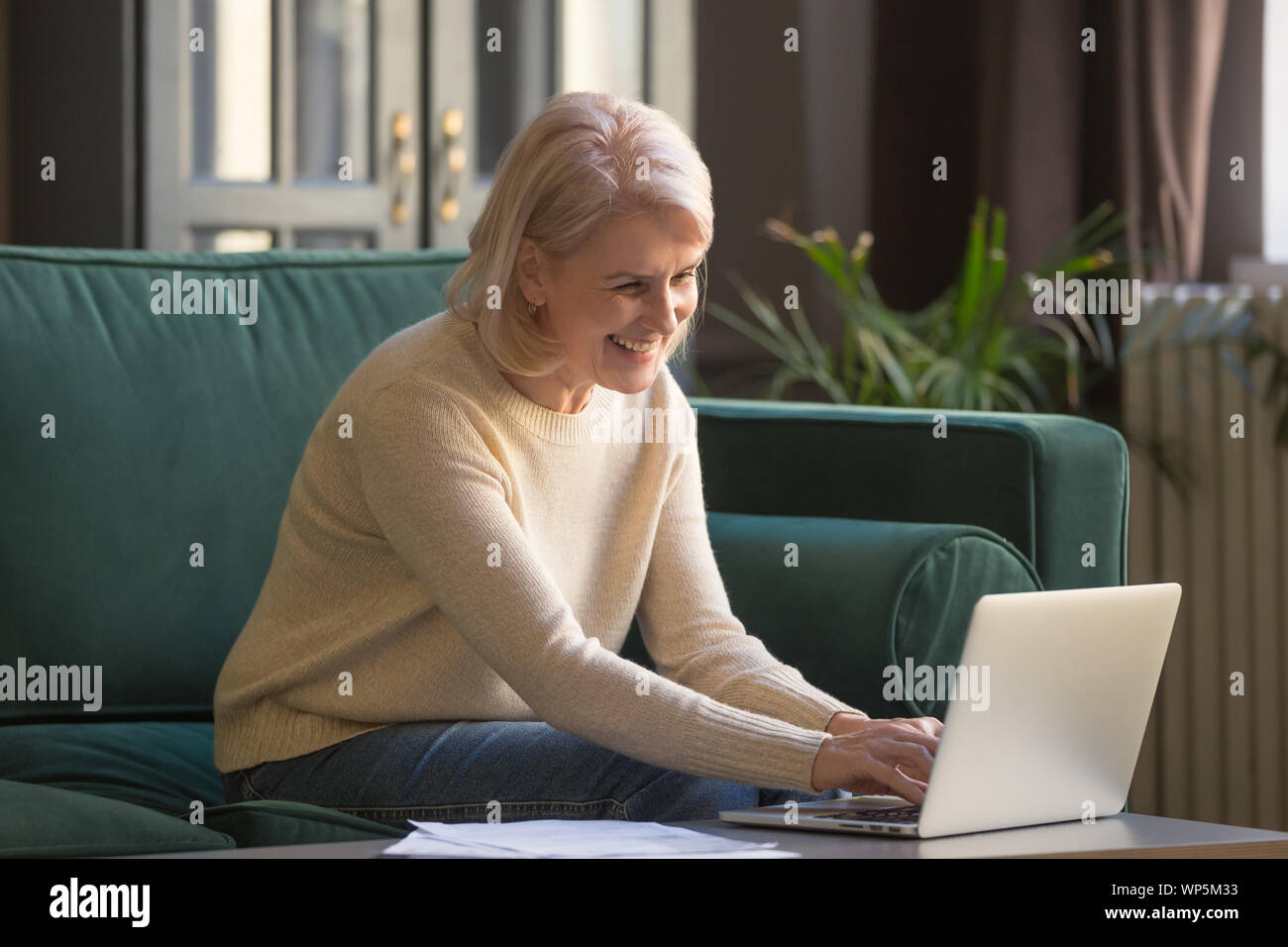 Lächelnd senior Frau fühlen Sie sich frei mit Laptop zu Hause Stockfoto