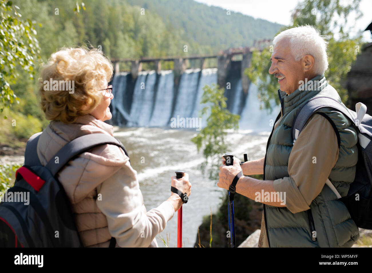 Gerne reifer Mann und Frau in Activewear sprechen in natürlicher Umgebung auf Reise Stockfoto