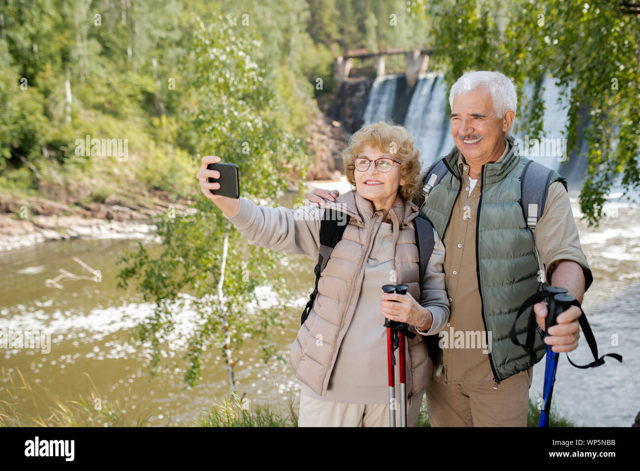 Lächelnd seniors mit Trekking Stöcke, selfie während Ihrer Reise Stockfoto