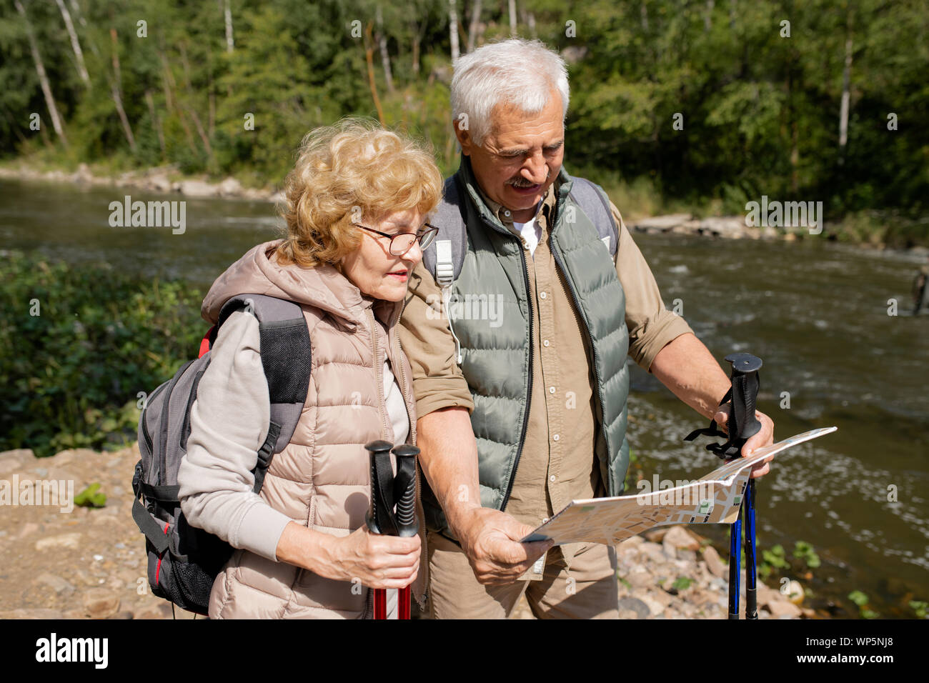 Moderne Senioren in Activewear auf guide Karte während Ihrer Reise Stockfoto