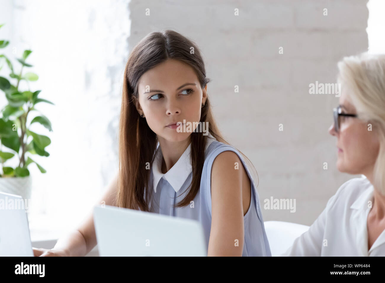 Ernsthafte weibliche Mitarbeiter blicken verärgert an Frau Kollege im Büro Stockfoto