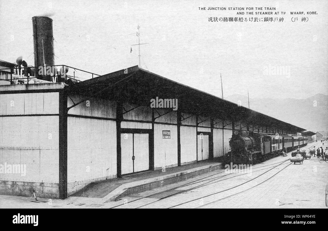 [1920s Japan - Dampflokomotive Kobe-hafen Junction Station] - eine Dampflokomotive und Pkw wartet an der Kobe-hafen Junction Station. Hinter dem Hafen Gebäude, die Stapel von einem Dampfer gesehen werden kann. 20. jahrhundert alte Ansichtskarte. Stockfoto