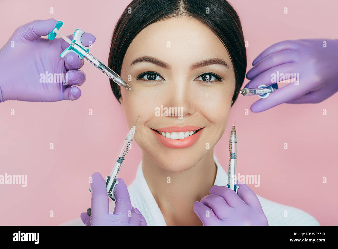 Asiatische Frau Werbung Konzept der Hautverjüngung mit Schönheit Injektion auf rosa Hintergrund. Menge Spritzen um ein weibliches Gesicht. Nicht-chirurgische Stockfoto