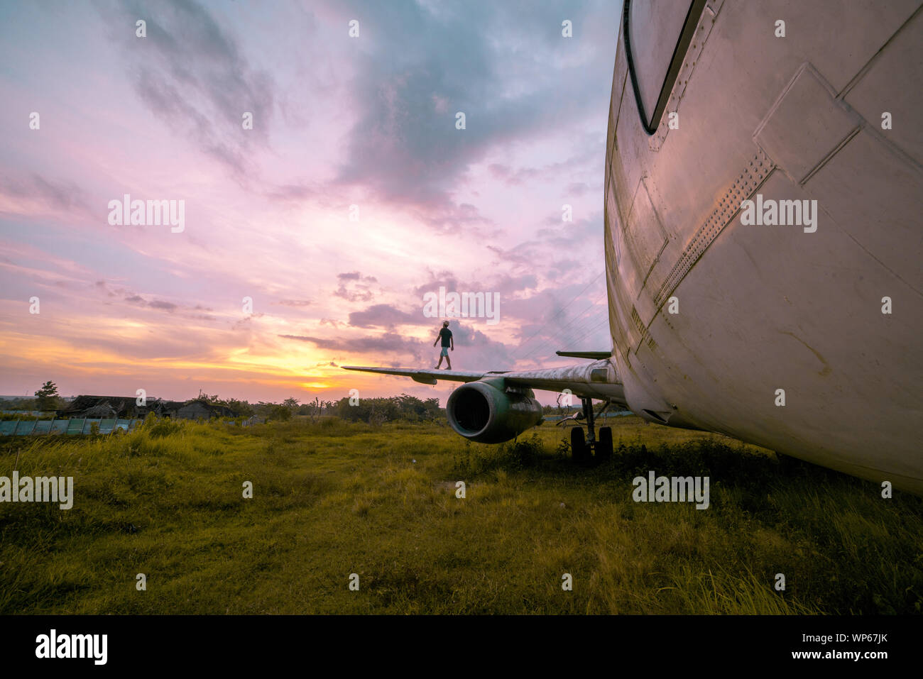 Kerl zu Fuß auf den Flügel eines verlassenen Flugzeug in der Mitte von Nirgendwo bei Sonnenuntergang Stockfoto