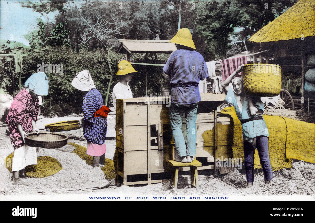 [1920s Japan - Japanische Bauern Worfeln Reis] - Japanische Bauern worfeln Reis mit einem toumi (唐箕, worfeln Maschine), Ca. In den 1880ern. Der Prozess der Trennung der Körner von der Spreu genannt wurde fusen (風選), und an eine Person die Fütterung der toumi mit Getreide, während ein anderer der Lüfter gedreht. Der Wind tat sein Übriges. Diese Postkarte ist aus einer Serie über die japanische Landwirtschaft, Landwirt das Leben in Japan. 20. jahrhundert alte Ansichtskarte. Stockfoto