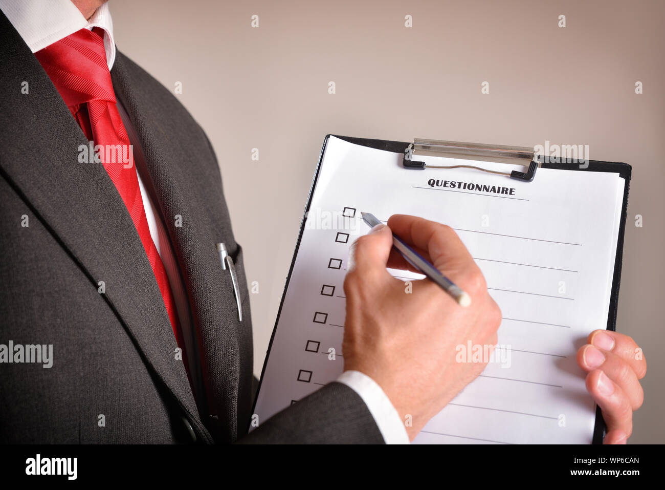 Mann im Anzug mit einem Fragebogen mit Blatt in einem Ordner und einen Bleistift in der Hand. Horizontale Komposition. Seitenansicht Stockfoto